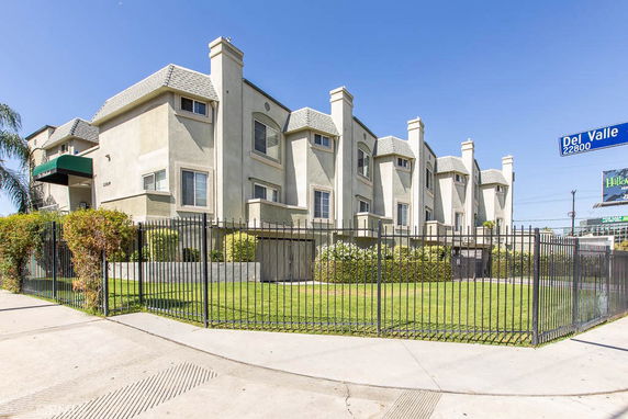 Front view of a multi-story residential building with gated entrance.