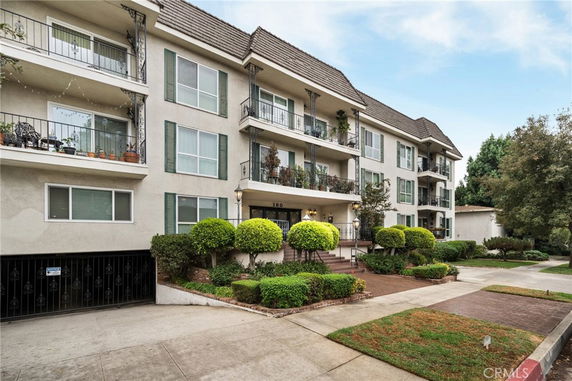 Front view of a multi-story apartment building with balconies and landscaped entrance.