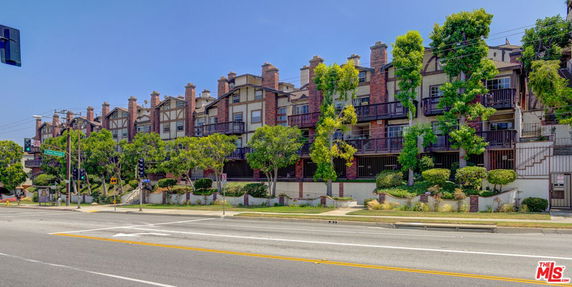 Front view of a multi-story residential building with balconies and brick accents.