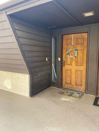 Front entryway of a building with a wooden door and wreath decoration.