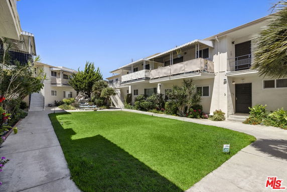 Front view of an apartment building with two stories and a central courtyard.