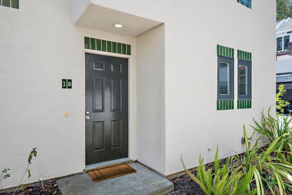 Front view of a house entrance with a black door and windows accented by green tiles.
