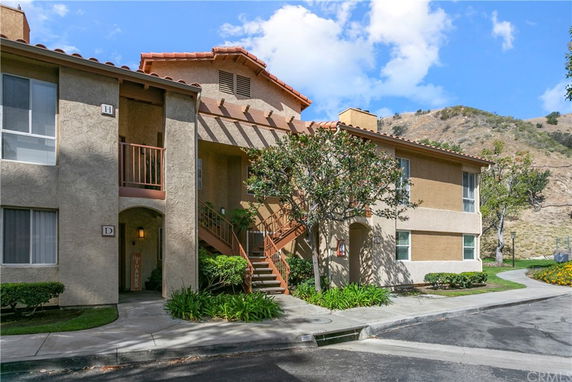 Front view of a two-story residential building with beige exterior and red-tiled roof.