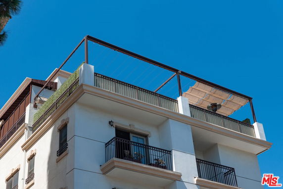 Front view of a multi-story building with balconies and a rooftop patio.