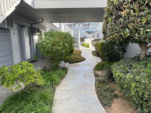 Front view of a multi-story building with a pathway and gardens.
