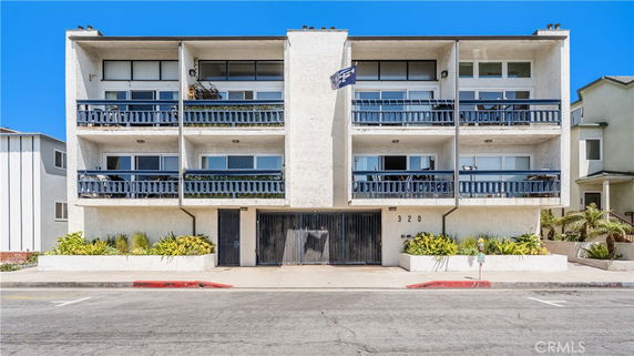 Front view of a multi-story building with balconies and a gated entrance.