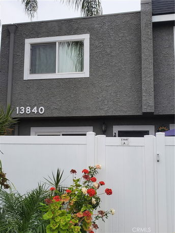 Front view of a two-story house with a window and white fence.