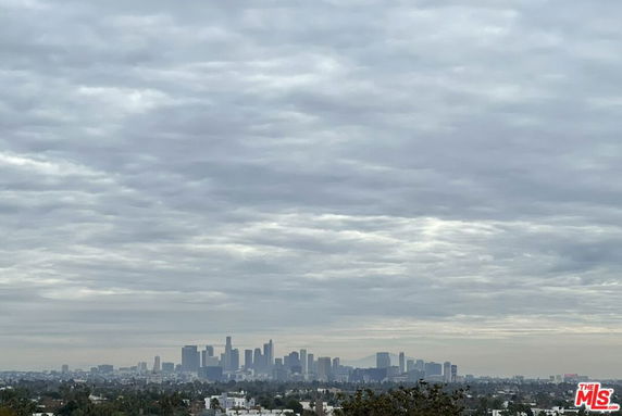 Panoramic view of a city skyline under a cloudy sky.