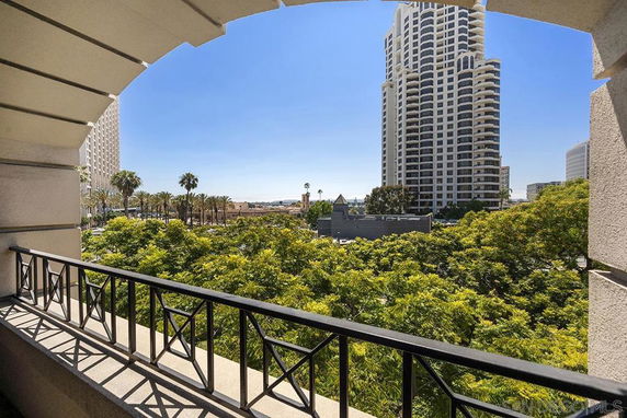 Panoramic view from a balcony showing greenery and tall buildings.