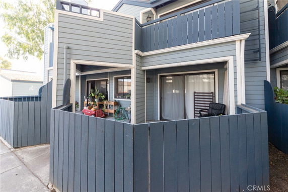 Front view of a two-story house with a fenced patio area.
