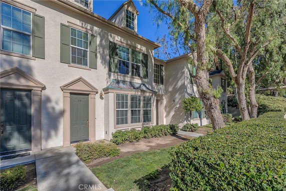 Front view of a two-story townhouse with green shutters and multiple entrances.