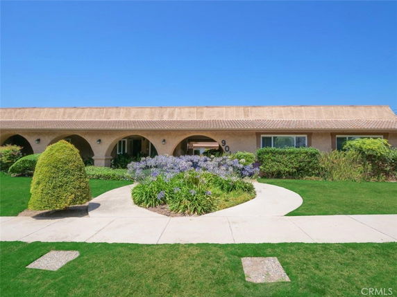 Front view of a single-story house with arched entryways and a well-maintained garden.