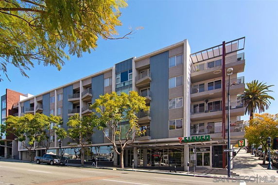Front view of a multi-story building with balconies and ground-floor retail space.
