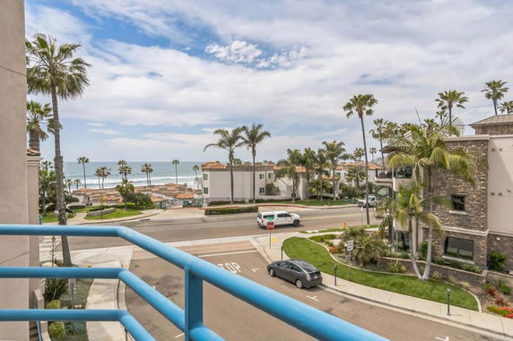 Panoramic view of a coastal area with buildings and palm trees near the ocean.