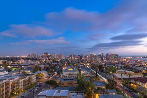 Panoramic view of a city skyline at dusk, with buildings and streets visible.