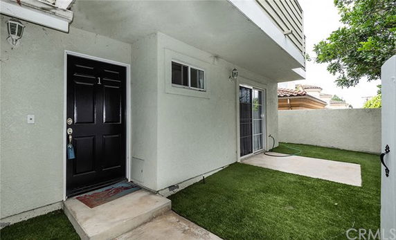 Front view of a house with a black door and a small porch area.