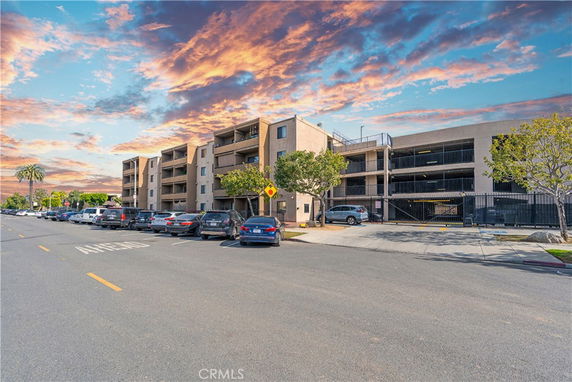 Front view of a multi-story apartment building with parking area.