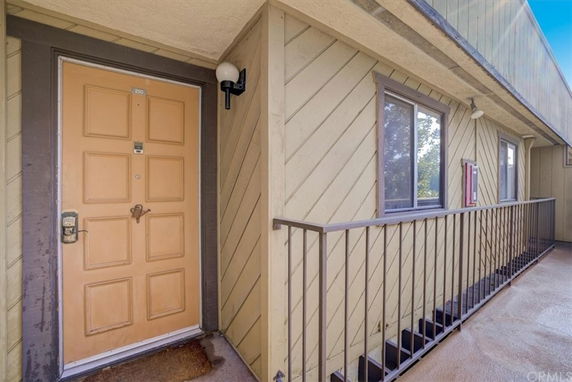 Front view of a building entrance with a beige door and metal railing.