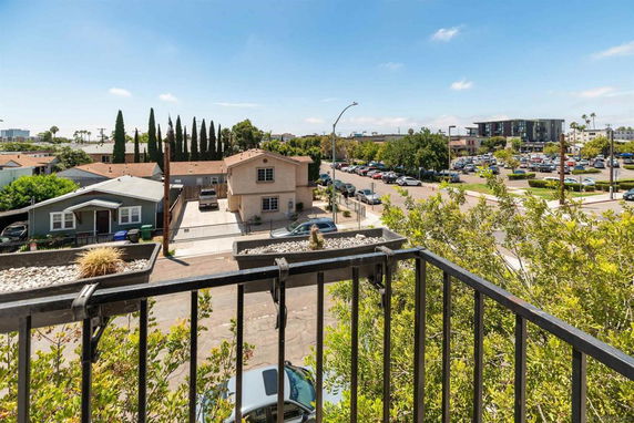 View from a balcony showing houses, a parking lot, and distant buildings.