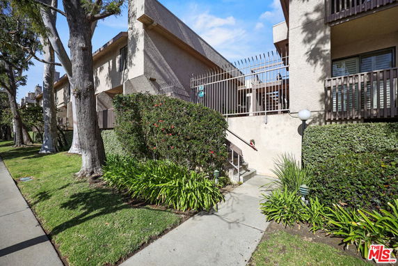 Front view of a multi-story building with balconies and a gated entrance.