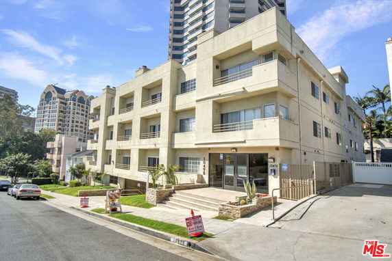 Front view of a multi-story apartment building with balconies and large windows.
