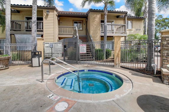 Small outdoor jacuzzi with a gated apartment building in the background.
