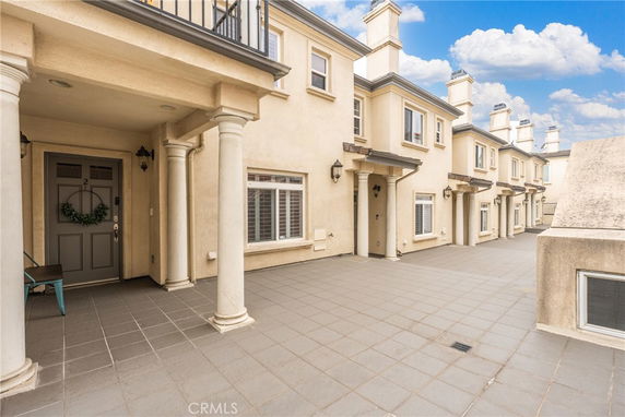 Front view of a row of townhouses with columns and covered entryways.