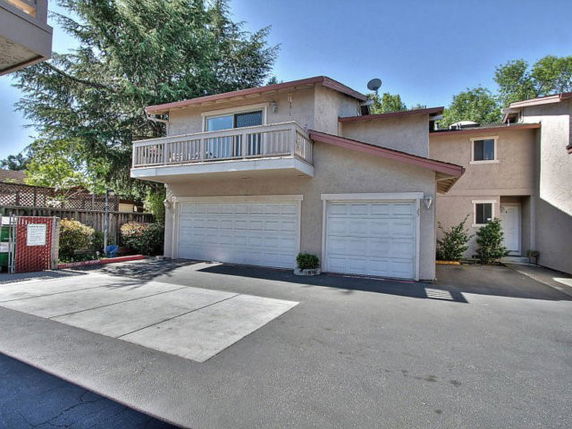 Front view of a residential building with a double garage and a balcony.