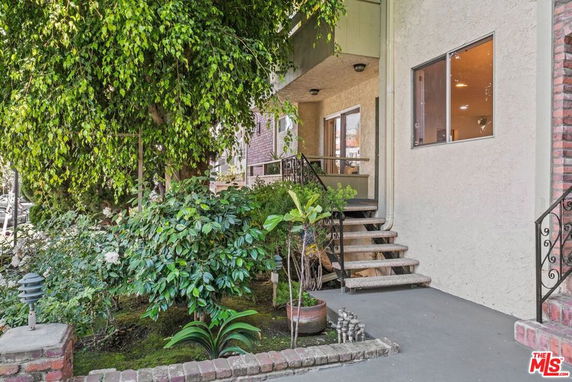 Front view of a house entrance with a staircase and garden.