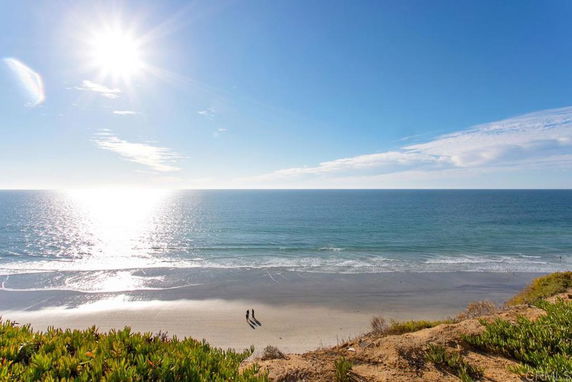 Panoramic view of the coastline with ocean and beach under a bright sun.