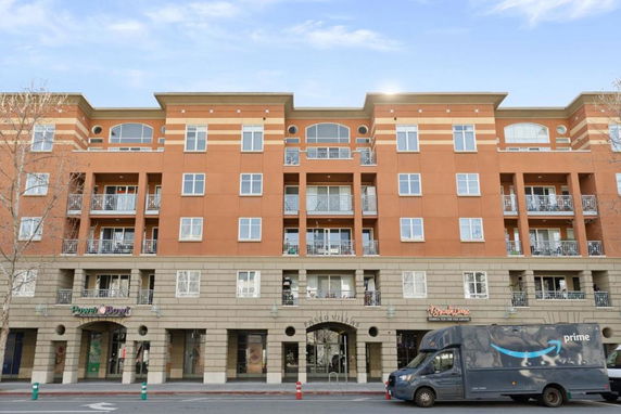 Front view of a multi-story apartment building with balconies and commercial ground floor.