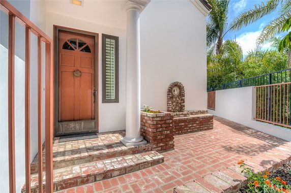 Front view of a house entrance with a wooden door and brick steps.