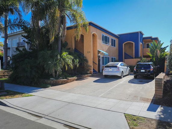 Front view of a two-story apartment building with a parking area in front.