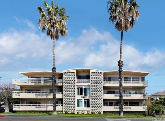 Front view of a three-story building with balconies and a decorative central facade.