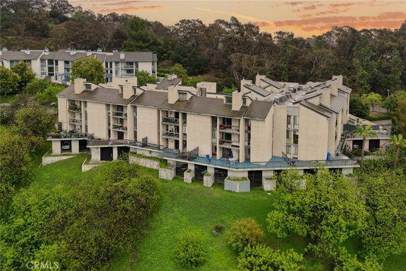 Front view of a multi-story residential building with multiple balconies and a sloped roof.