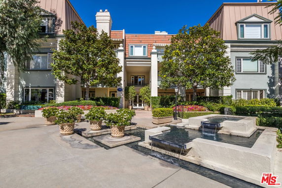 Front view of a multi-story building with a decorative water feature and landscaped entrance.