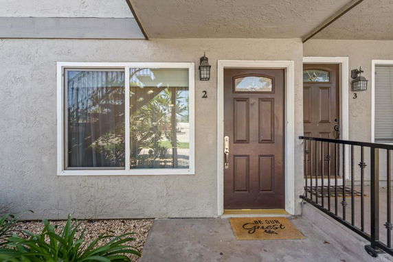 Front view of a building entrance with two solid brown doors and a window.