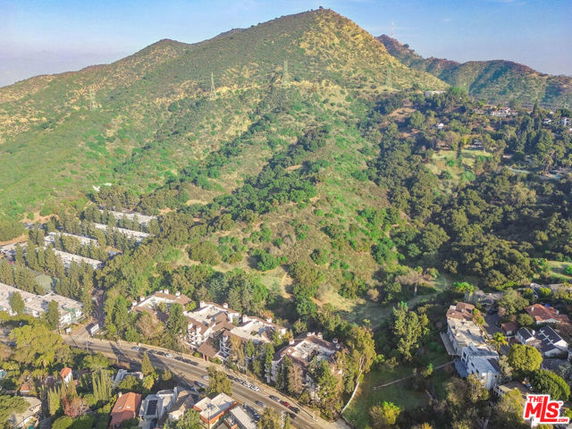 Aerial view of a hilly landscape with houses and lush greenery.