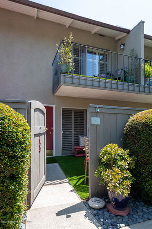 Front view of a two-story house with a balcony and small entrance area.