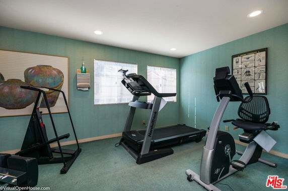 Room with exercise equipment including a treadmill and stationary bike.