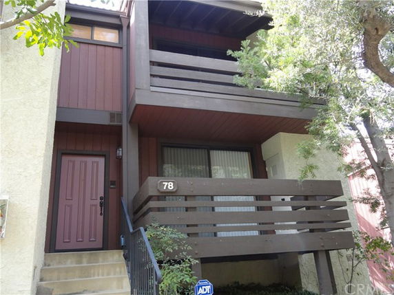 Front view of a two-story house with a balcony and staircase leading to the entrance.