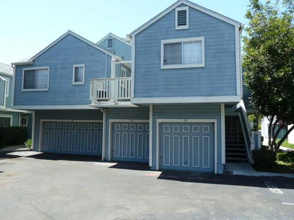 Front view of a blue multi-unit residential building with garages.