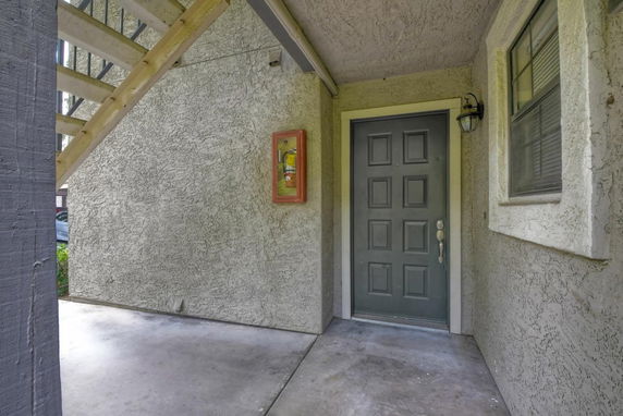 View of a building entrance with a textured wall and a dark door.