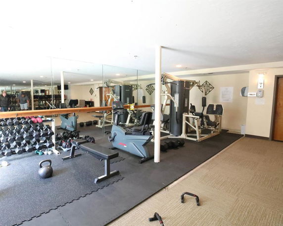 Indoor gym area equipped with fitness machines and free weights.