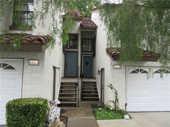 Front view of a house with a staircase leading to a double-doored entrance, flanked by two garages.