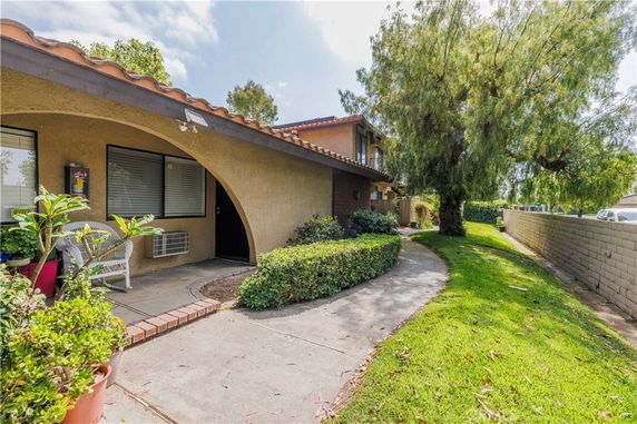 Front view of a house with an arched entrance and sidewalk.