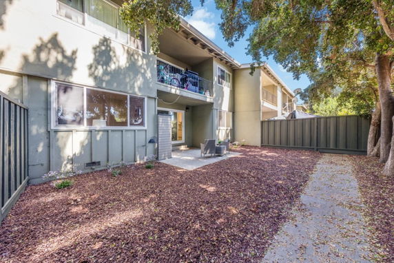 Rear view of a two-story building with balconies and a fenced yard.