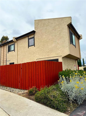 Front view of a two-story house with a red wooden fence.