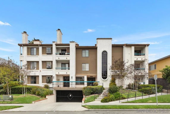 Front view of a multi-story residential building with balconies and a central vertical window.