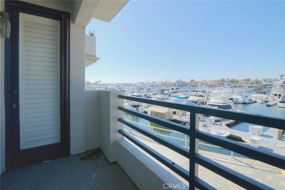 Balcony view overlooking a marina with boats docked and distant buildings.